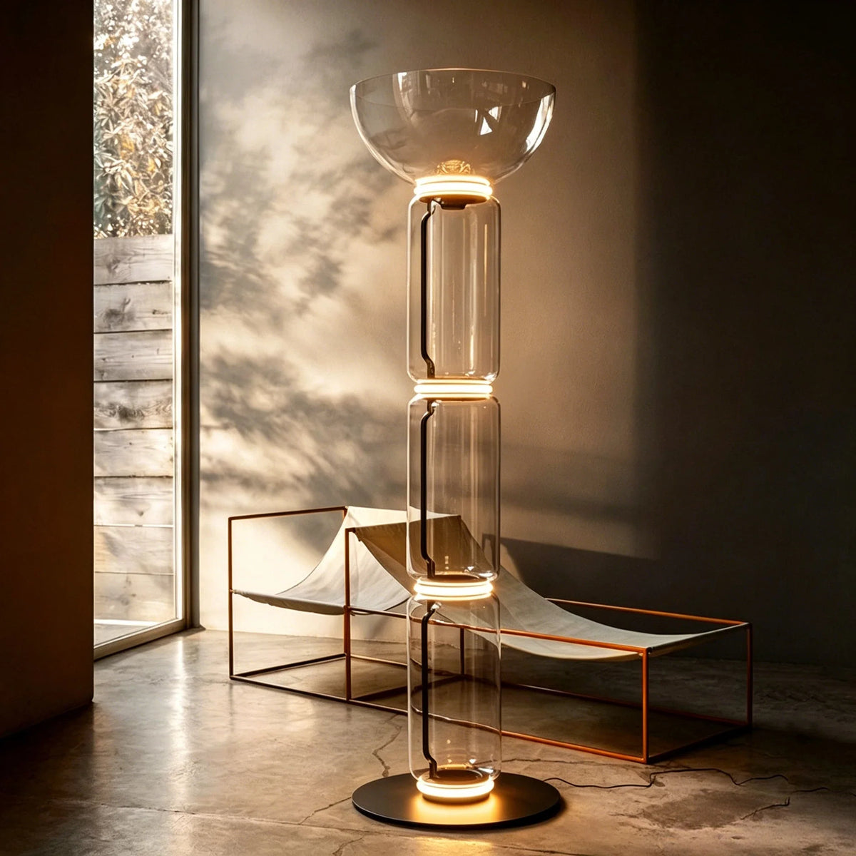 Glass floor lamp with warm-lit clear bowl shade and cylindrical glass body.