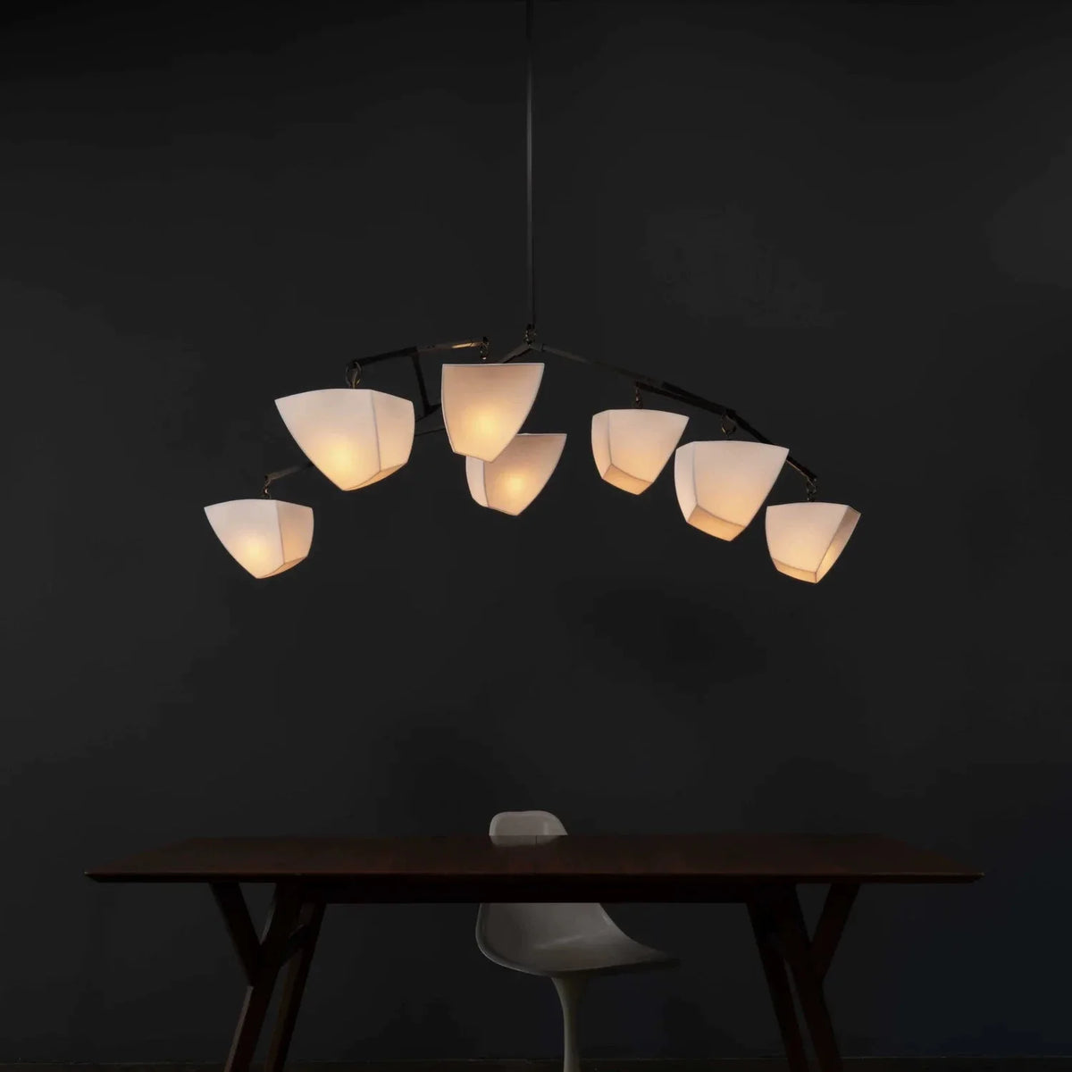 Brass branching chandelier with multiple off-white cone shades casting warm light