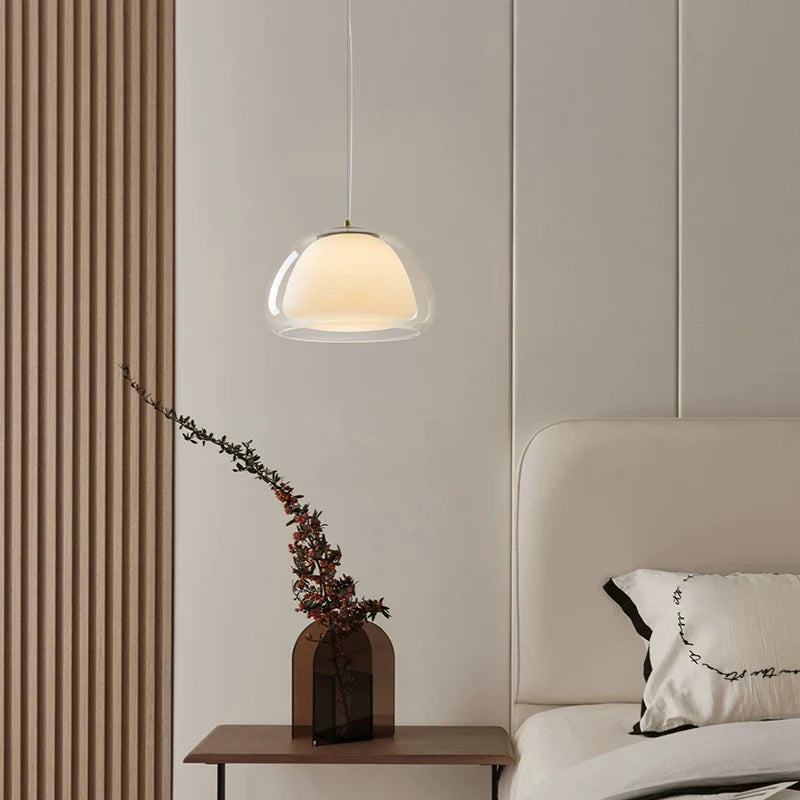Curved glass pendant light with clear glass bell shade, warm light filling the dome.