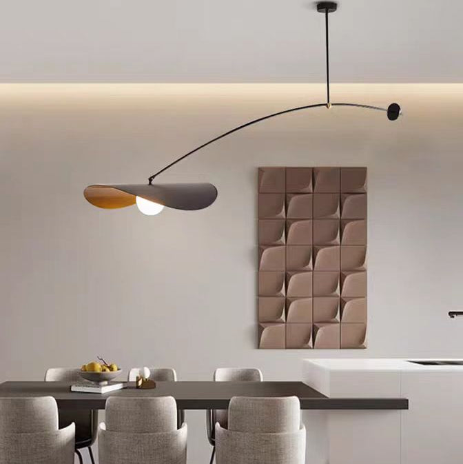 Single-arm pendant light with black curved arm and gold underside shade and lit bulb