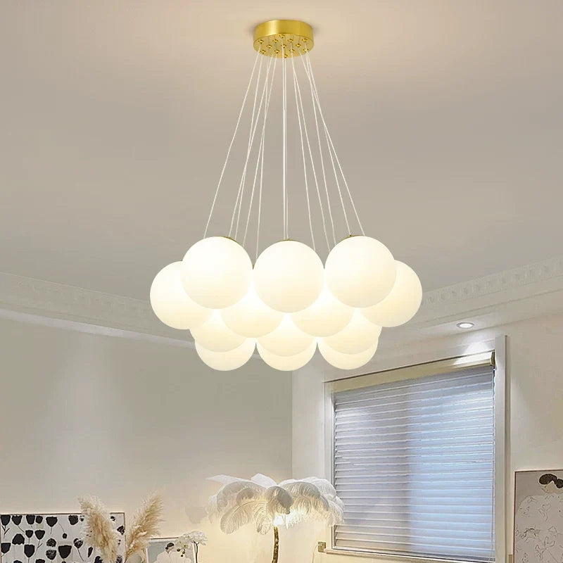 Multi-arm globe chandelier with gold canopy and five hanging frosted glass globes