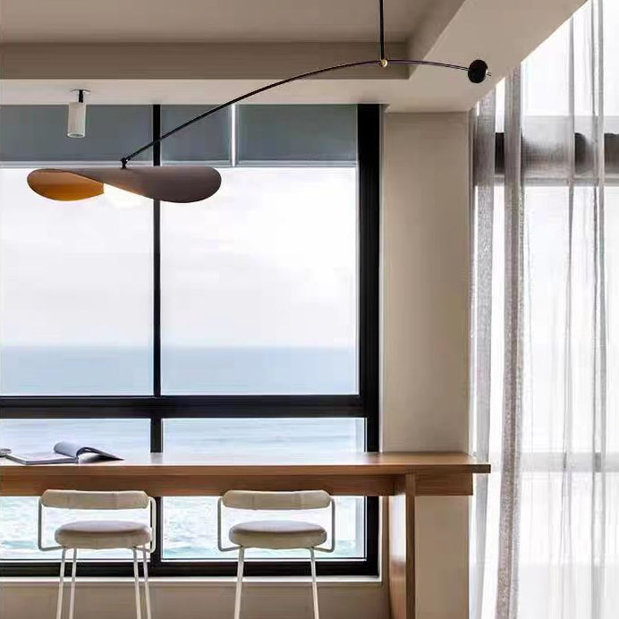 Single-arm pendant light with black arm and gold inner shade near large window