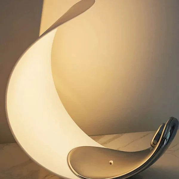 Crescent moon table lamp with white curved shade and metallic warm interior