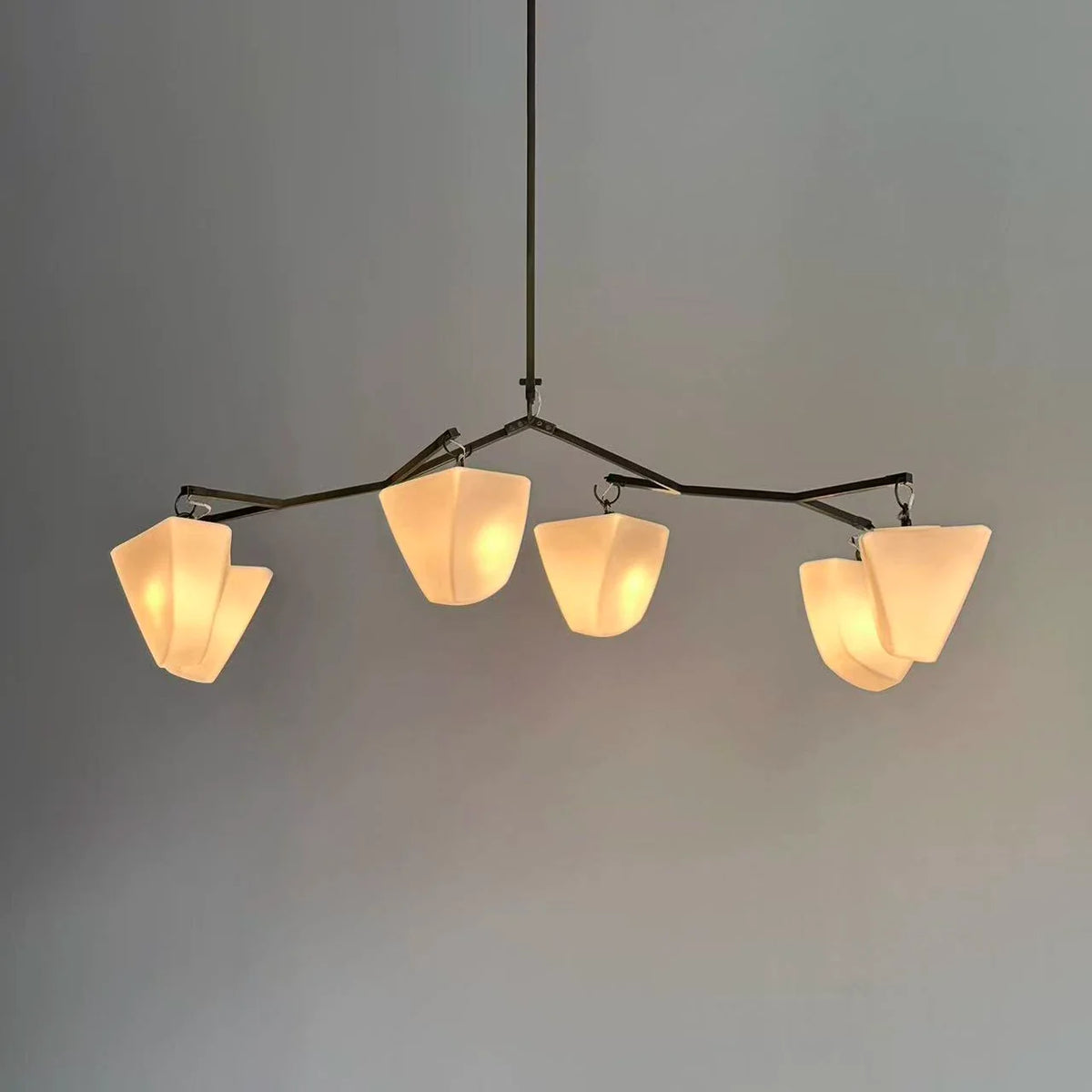 Brass branching chandelier with six off-white cone shades and adjustable hanging mounts
