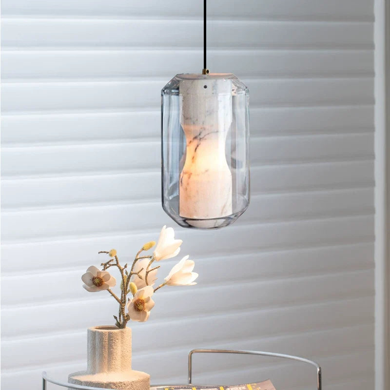 Solene alabaster and glass pendant light with clear faceted shade against wall