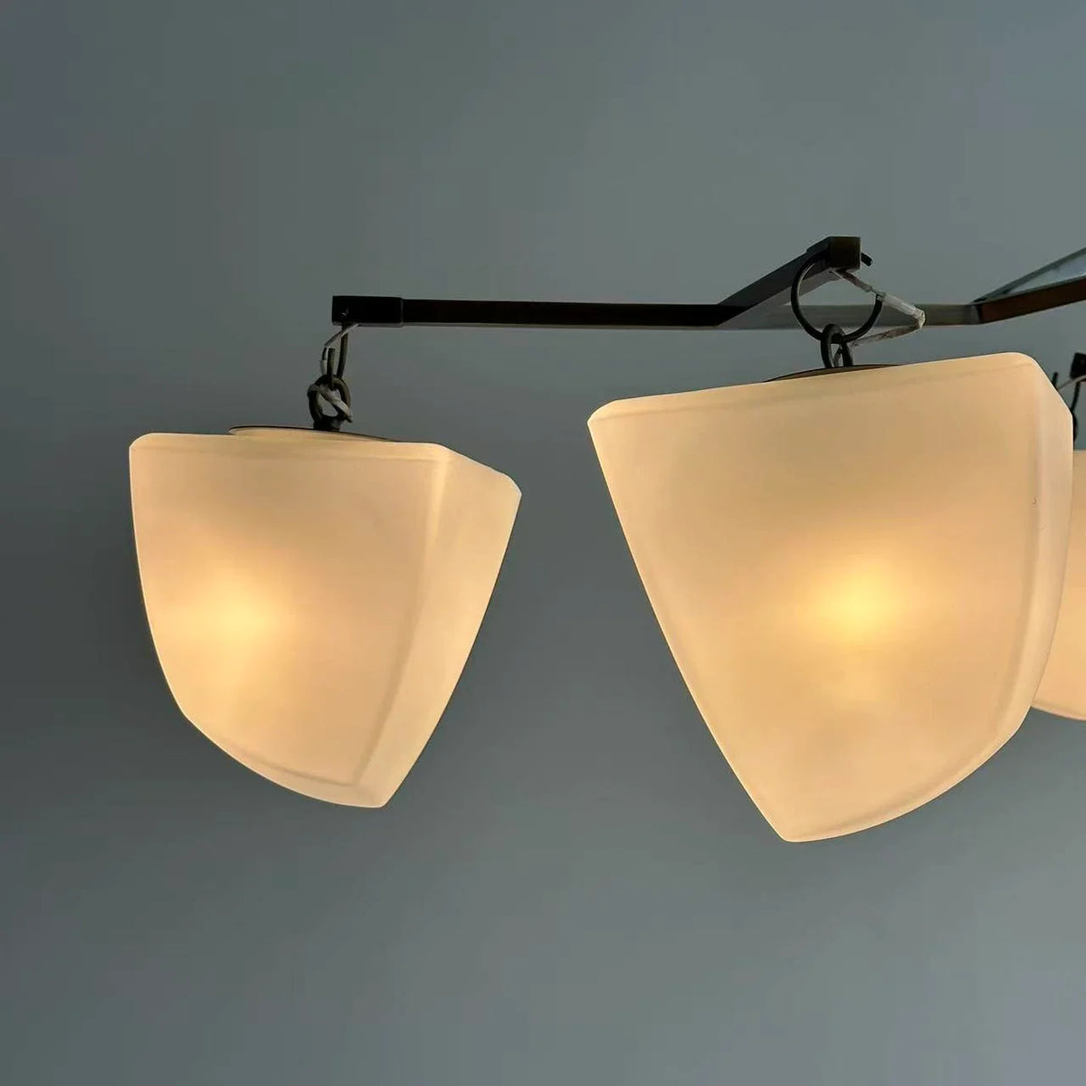 Brass branching chandelier close-up with two off-white fabric cone shades on bar arms