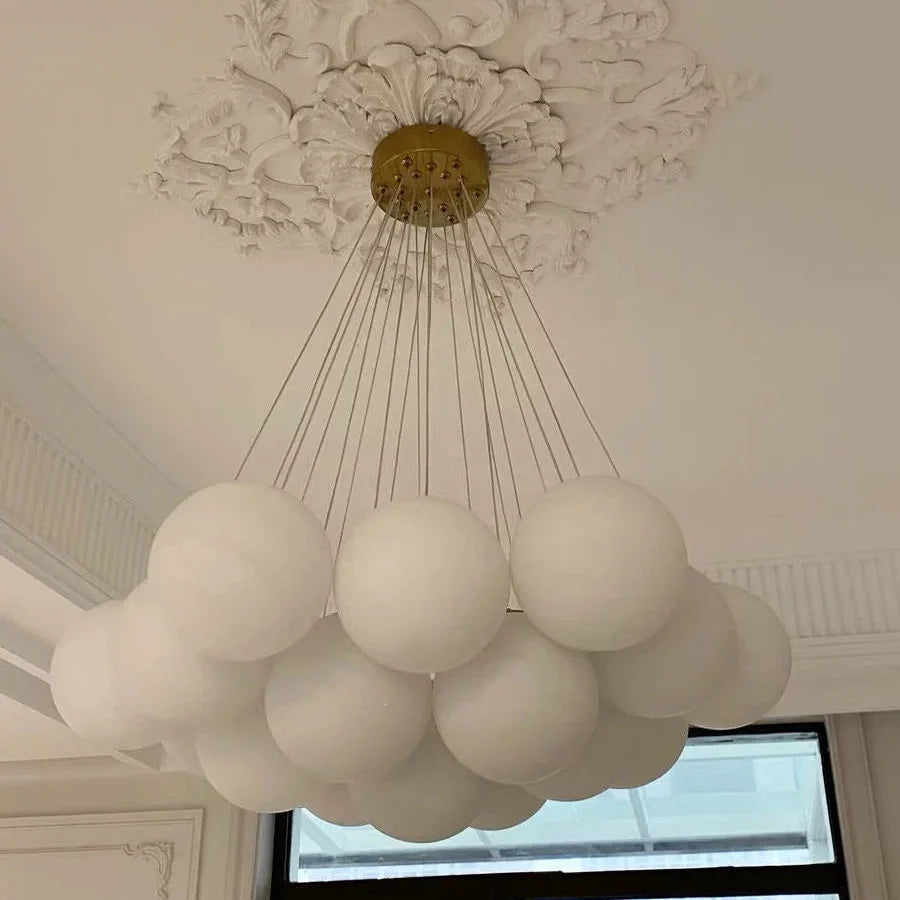 Multi-arm globe chandelier with gold ceiling plate and dense array of frosted globe shades