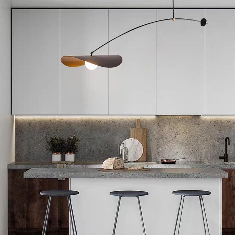 Single-arm pendant light with black arm and gold inner shade above kitchen counter