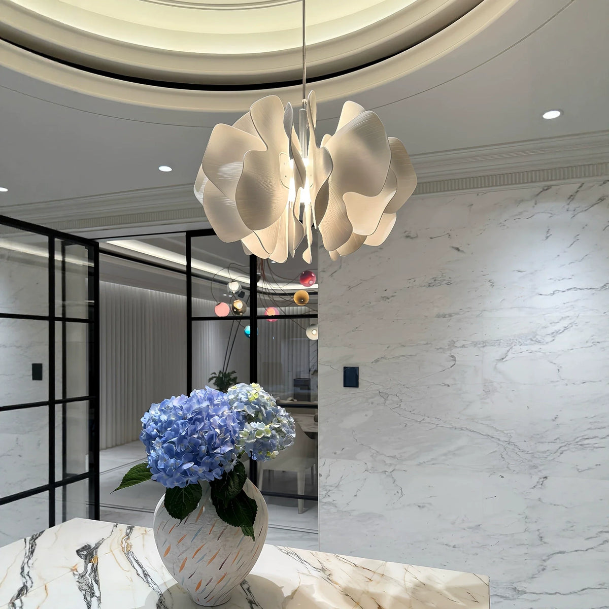 Ceramic petal chandelier overhead with warm-lit white petal shades and hanging cord