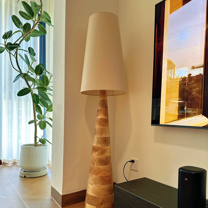 Wood floor lamp with off-white drum shade and carved tapered base