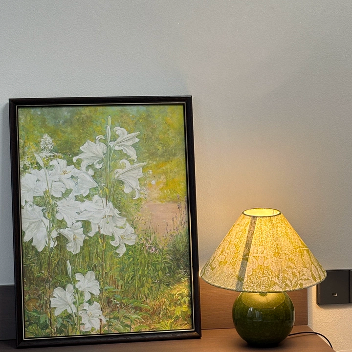 Ceramic table lamp with green spherical base and botanical patterned fabric shade, warm glow