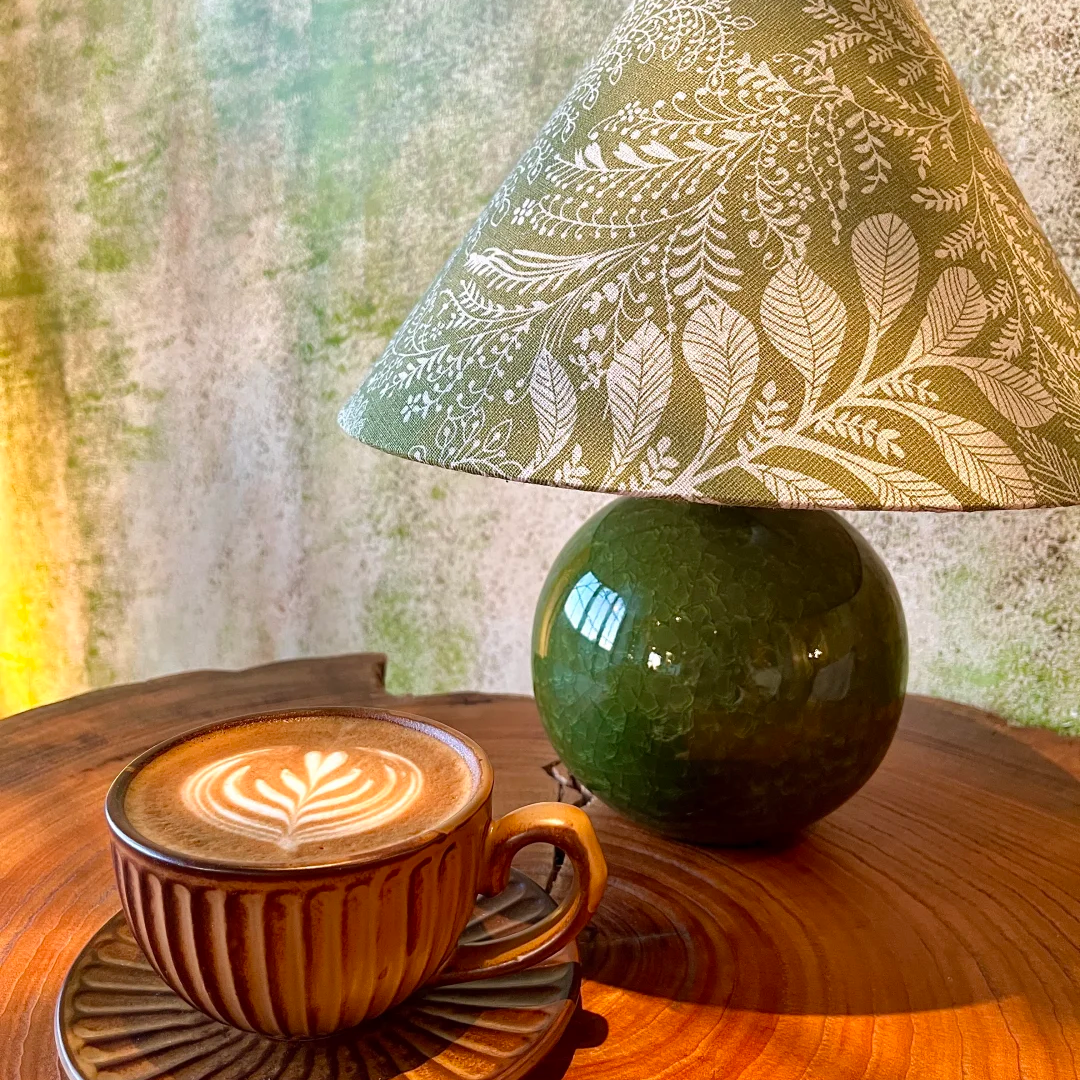 Table lamp with green ceramic sphere base and cone shade featuring gold leaf botanical print