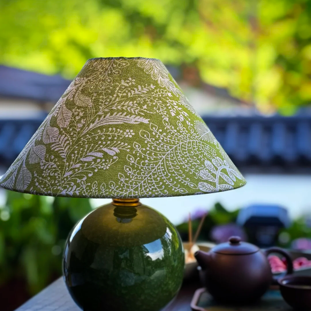 Outdoor view of ceramic table lamp with green globe base and green botanical lampshade