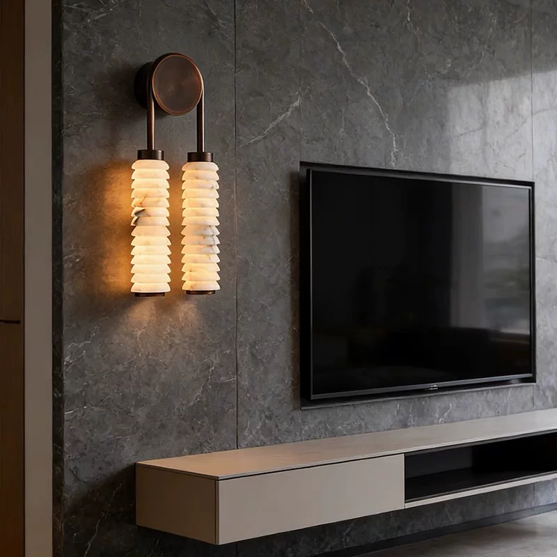 Tiered alabaster wall sconce with two illuminated stacked alabaster shades on dark metal bases