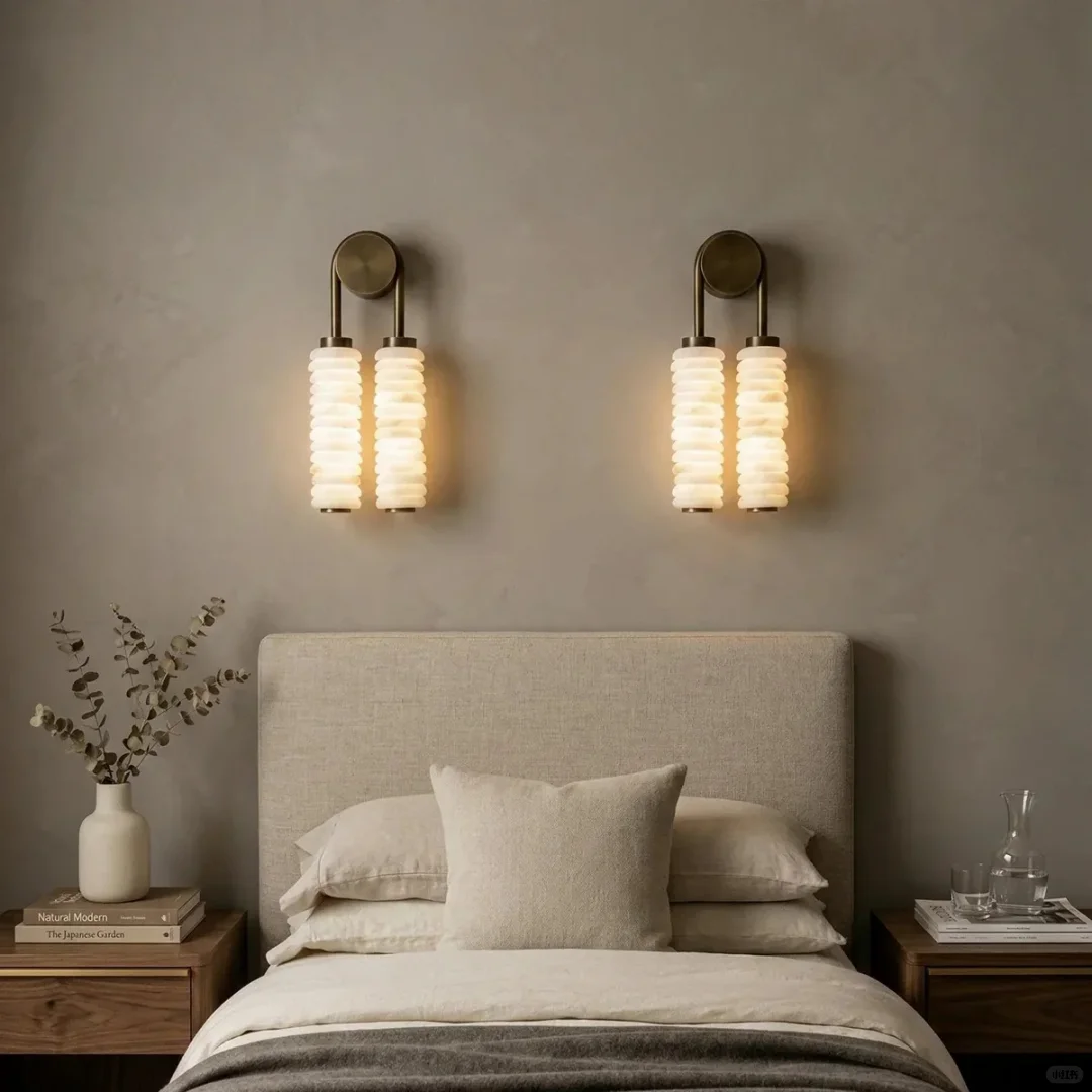 Tiered alabaster wall sconces with two glowing stacked cylindrical shades on round brass plates