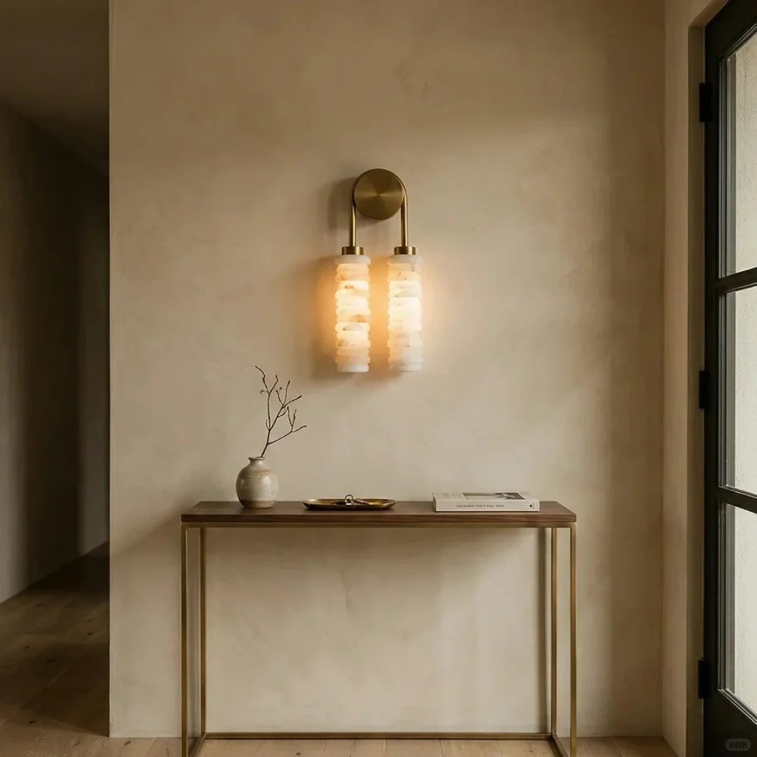 Pair of tiered alabaster wall sconces with glowing stacked cylindrical shades on round brass plates