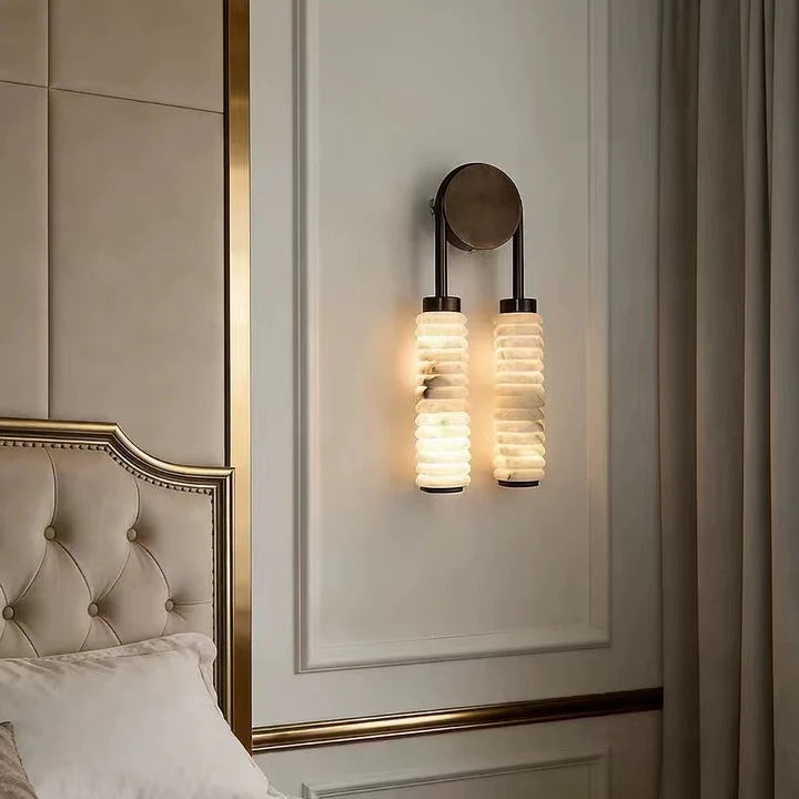 Tiered alabaster wall sconce with two stacked shade columns and dark metal round backplate