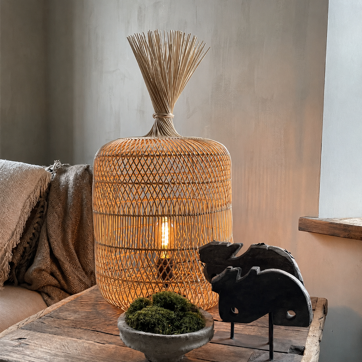 Natural rattan floor lamp on wooden surface, woven drum shade with warm bulb glow