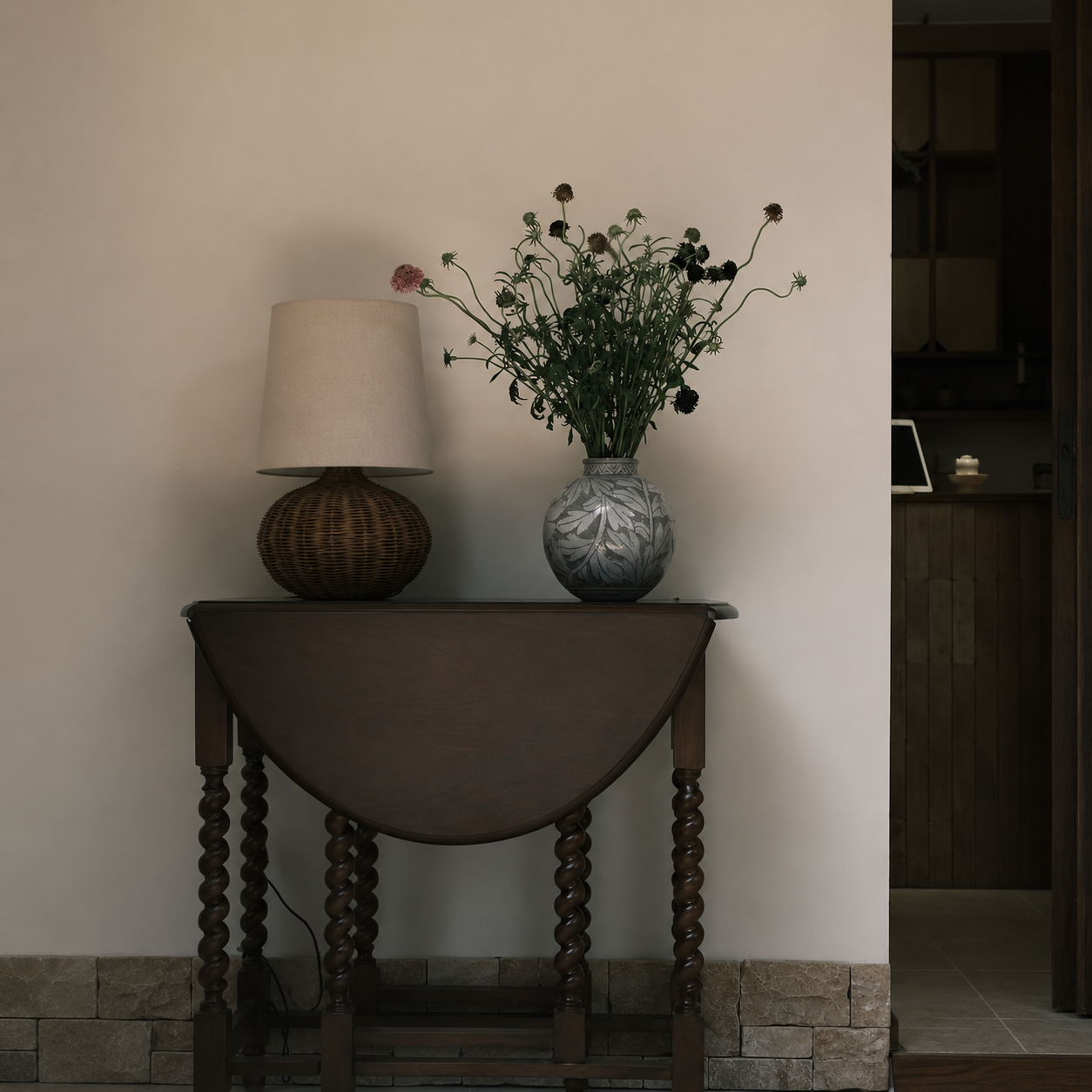 Woven rattan table lamp with off-white drum shade and rounded base.