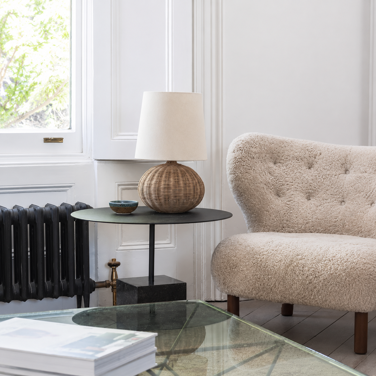 Rattan table lamp with cream drum shade and rounded woven base.