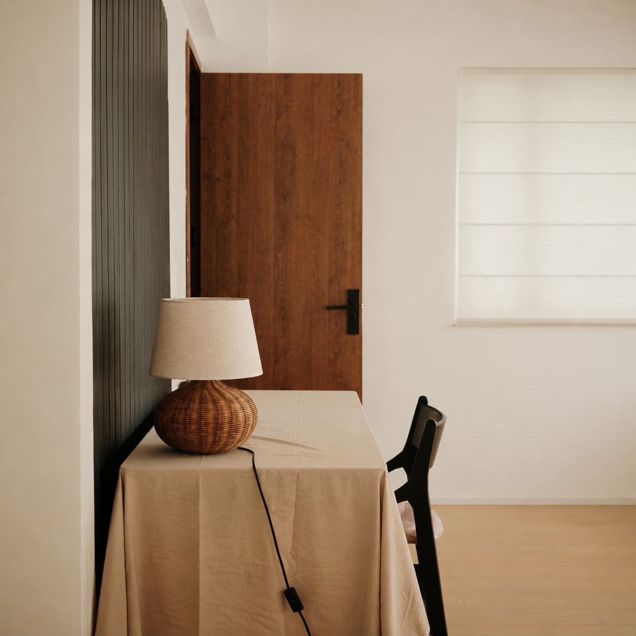 Rattan table lamp with beige fabric drum shade and woven rounded base.