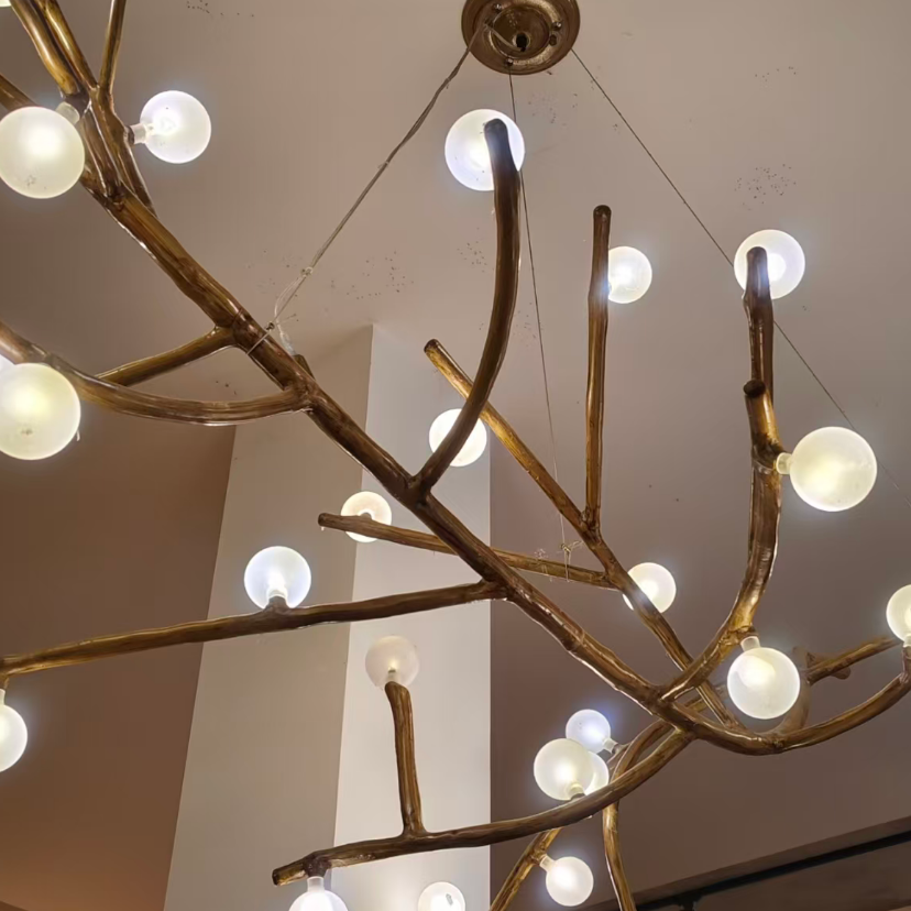 Close-up detail of gold branch chandelier with glowing round globe bulbs.