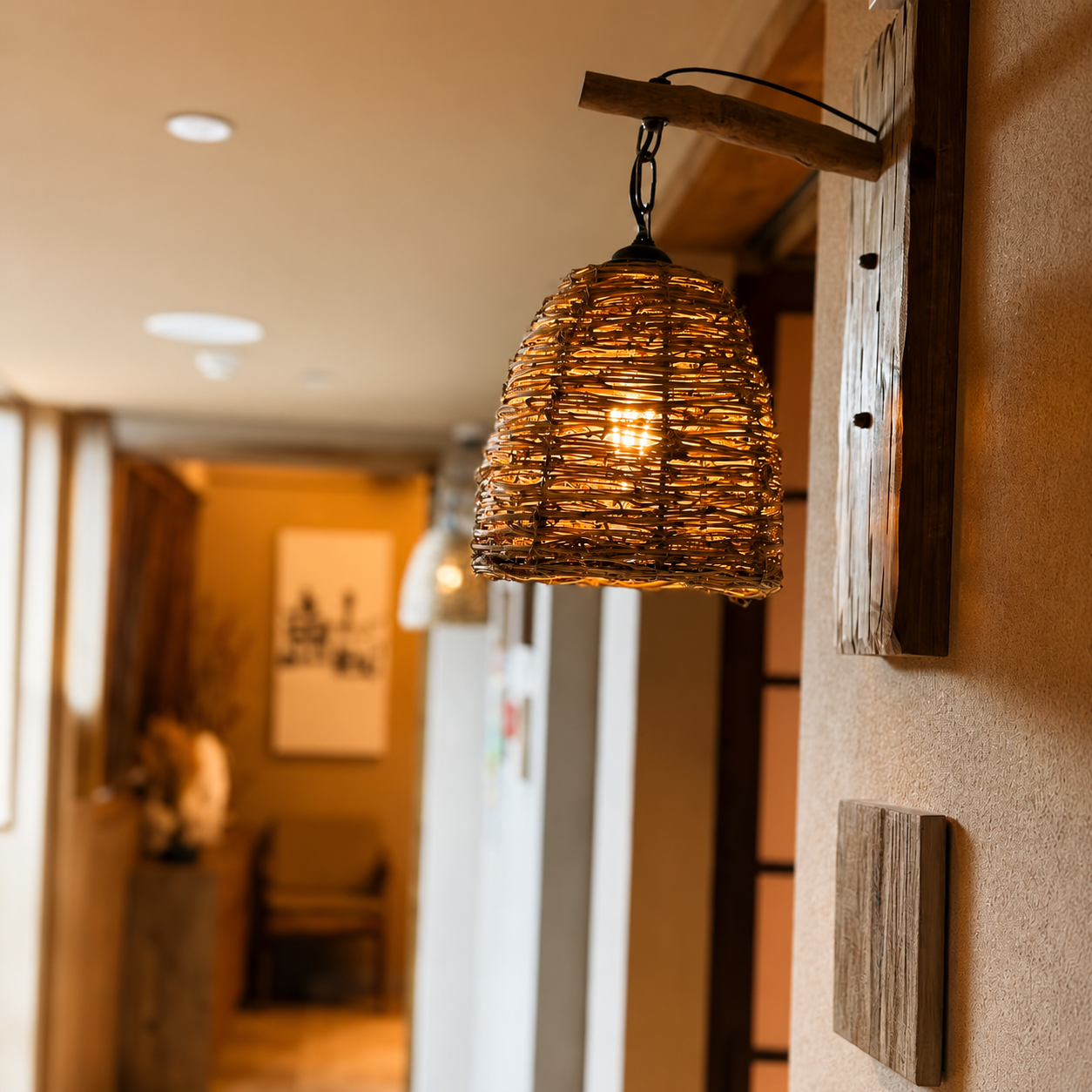 Woven pendant-style wall lantern with dark chain and wood arm, warm light shining