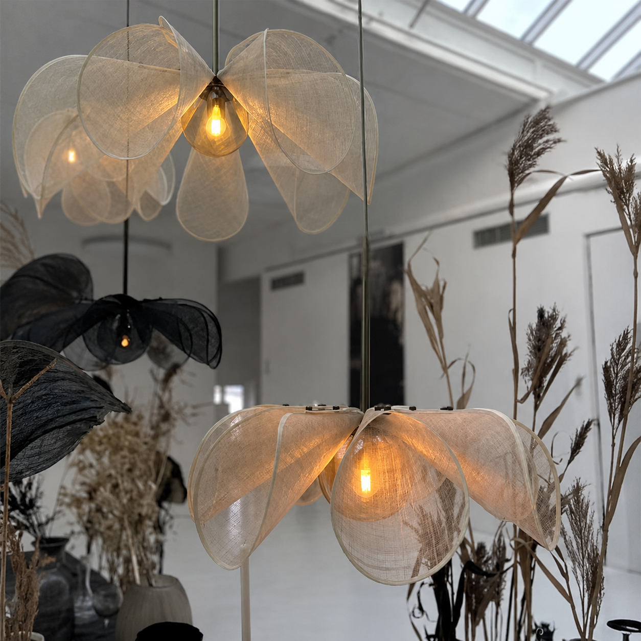 Linen petal chandelier with glowing bulb, translucent fabric shades, brass stem