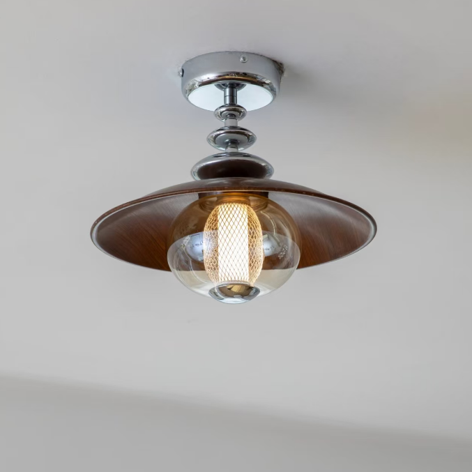 A modern ceiling light fixture with a wide, shallow dark brown wooden shade, a polished silver chrome canopy and stem, and a clear glass globe bulb housing a warm glowing Edison-style filament.