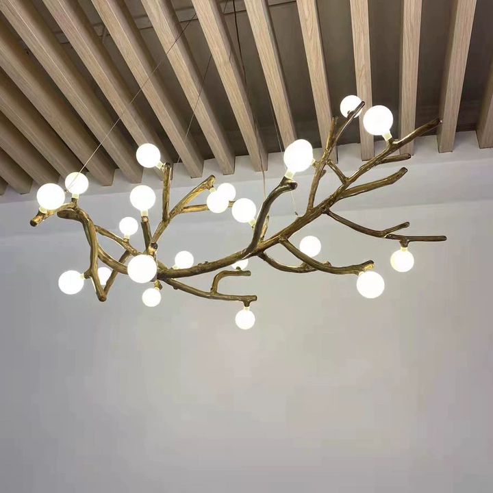 Close-up of gold branch chandelier with round globe bulbs under wood ceiling beams.