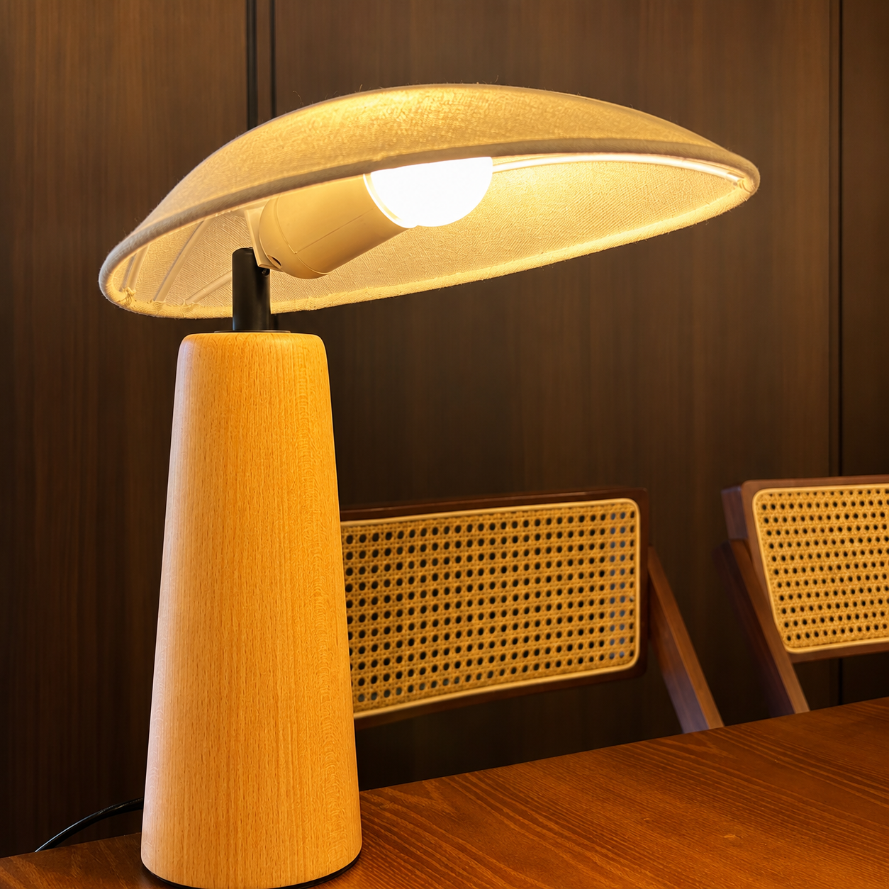 Wooden table lamp with linen shade, black socket, and warm-glowing bulb