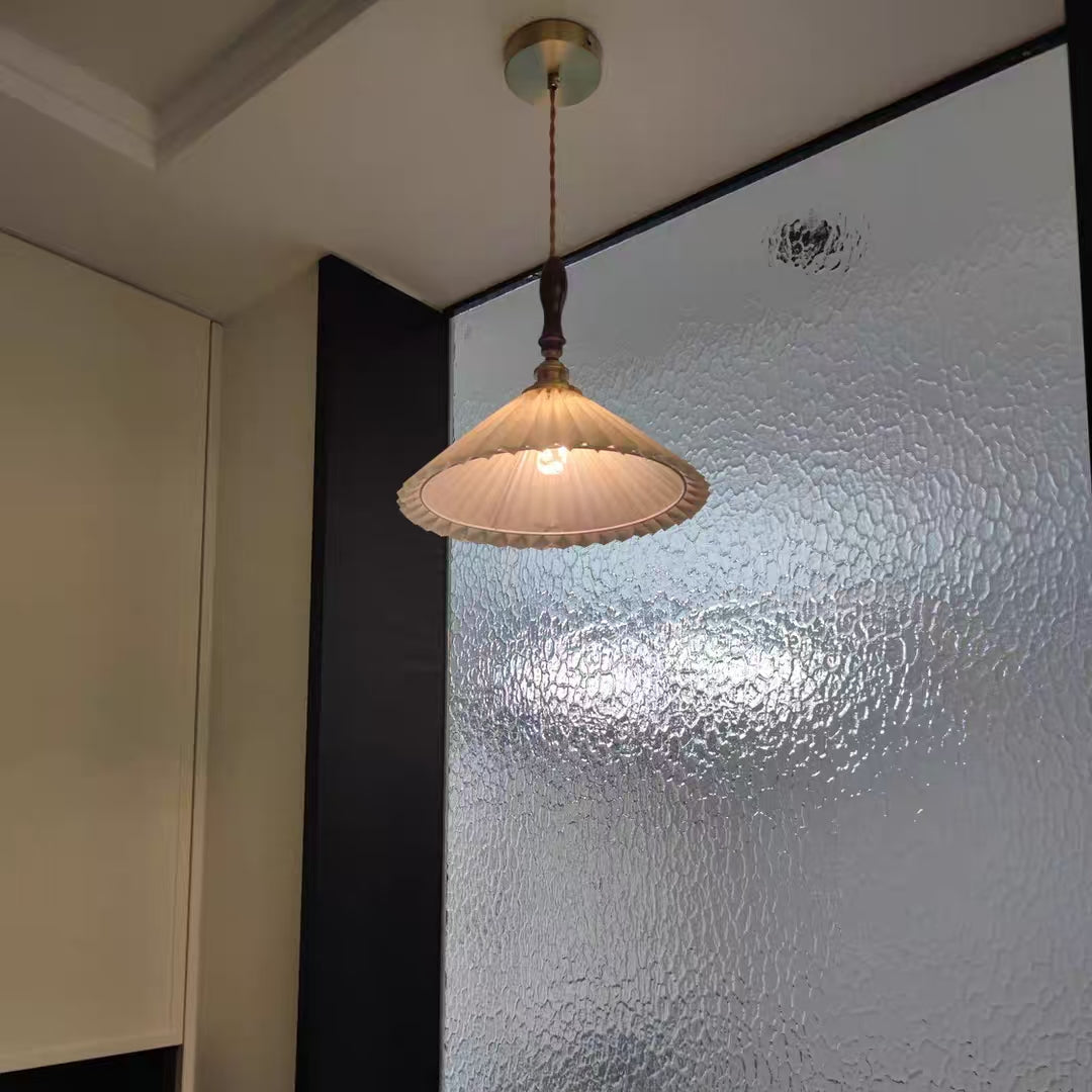 Pendant light with white fluted dome shade, dark wood top, and brass mounting hardware