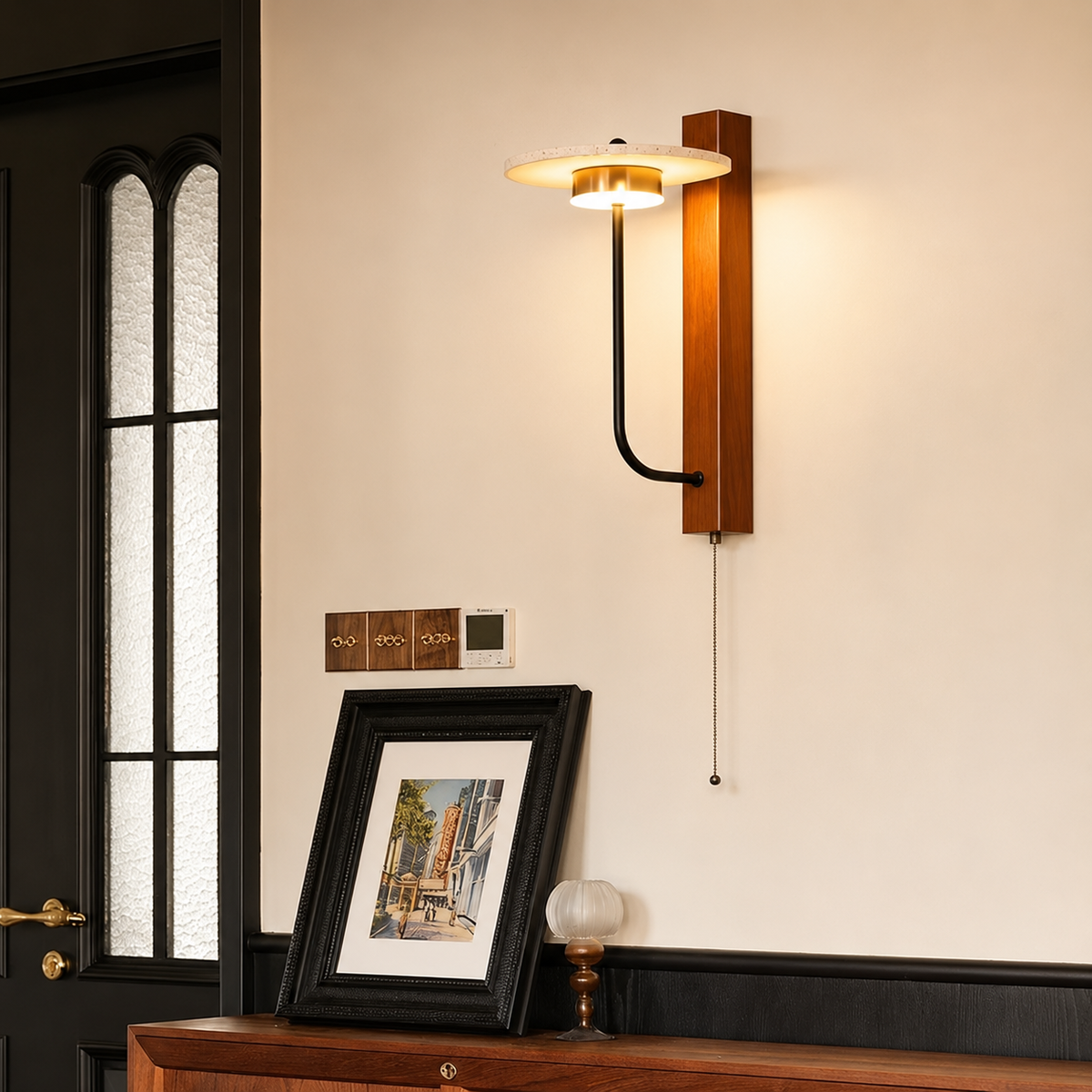 Wood wall sconce with halo light shade and curved black arm above framed art