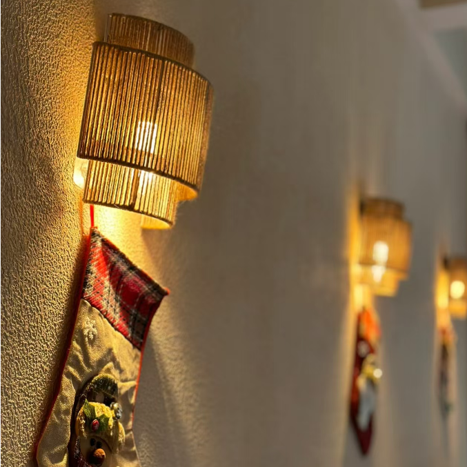 Wall sconce with cylindrical woven rope drum shade, warm light through vertical slits