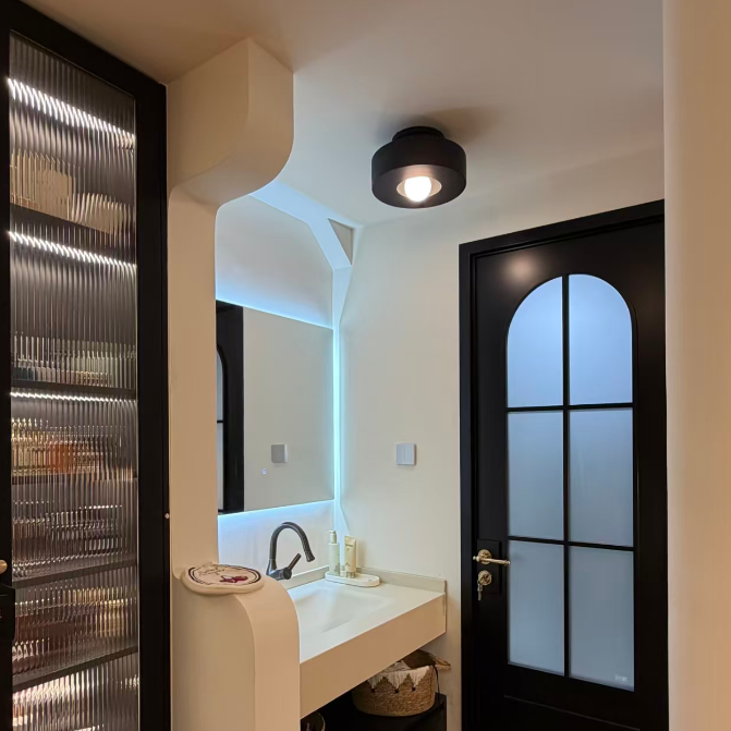 Black resin flush mount ceiling light with round shade and warm glowing lamp
