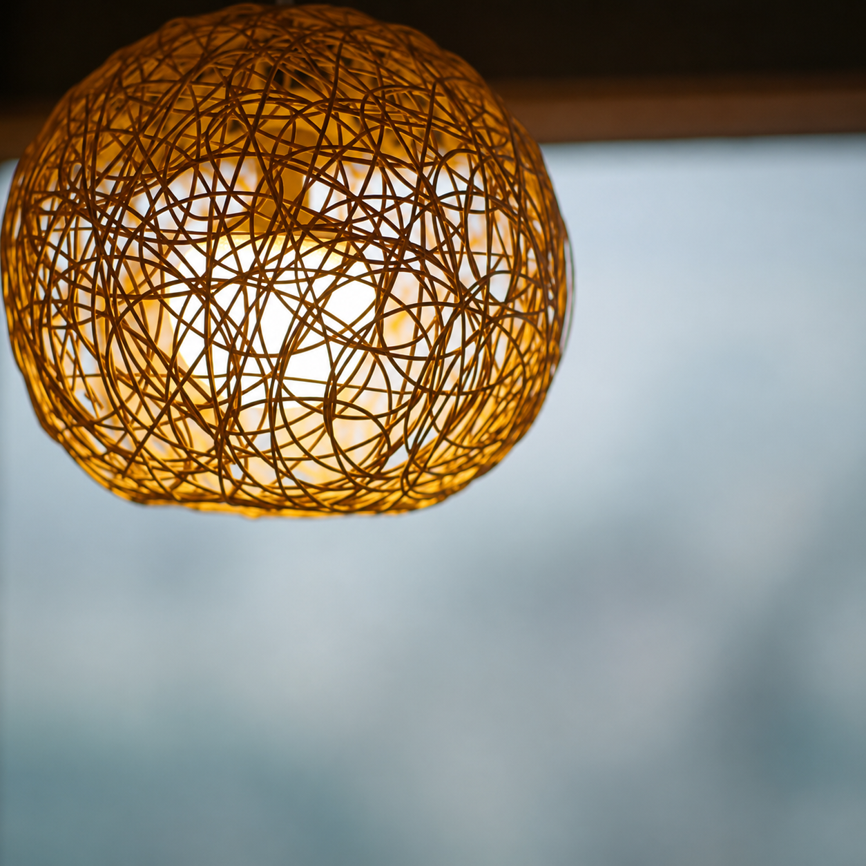 Close-up rattan orb pendant light with woven lattice shade and warm light glow