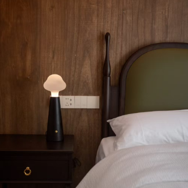 Cloud glass table lamp on nightstand with matte black base and frosted shade