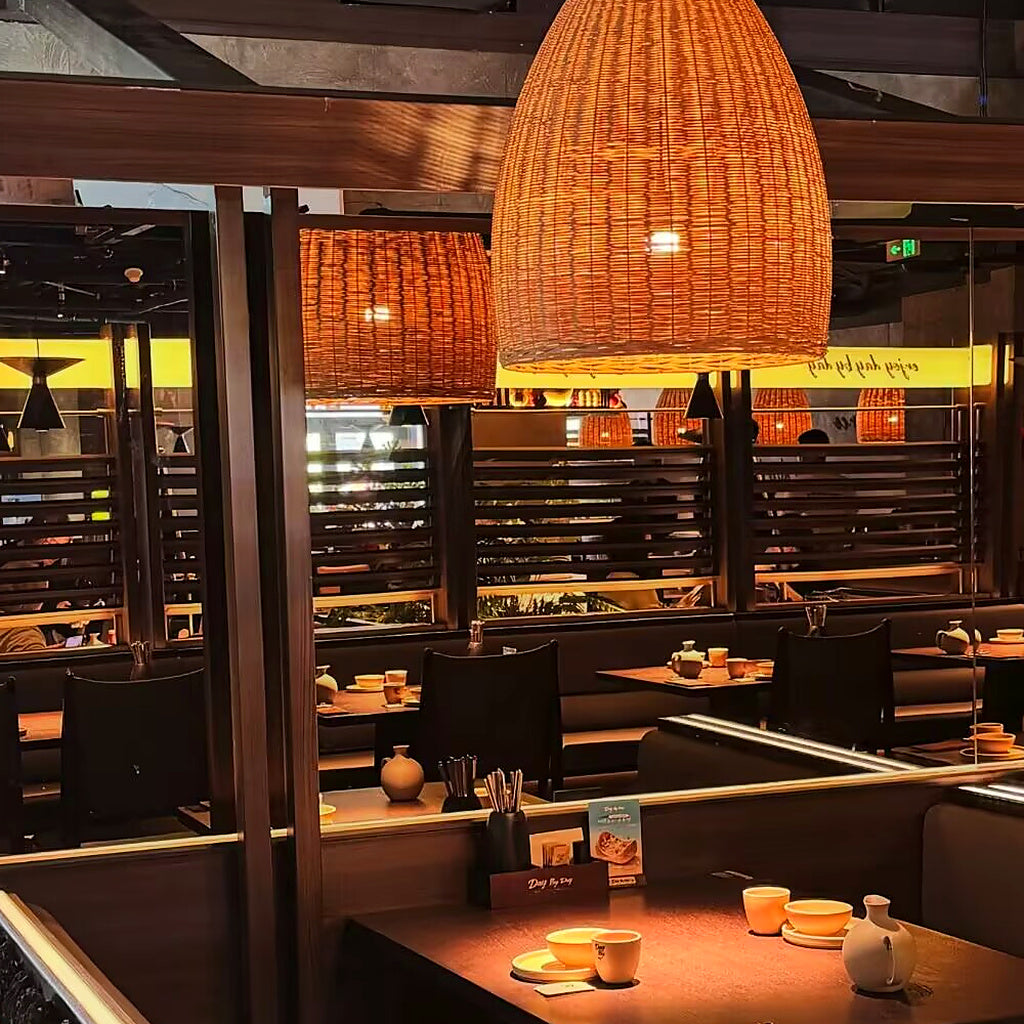 Rattan bell pendant light with tall woven conical shade glowing overhead